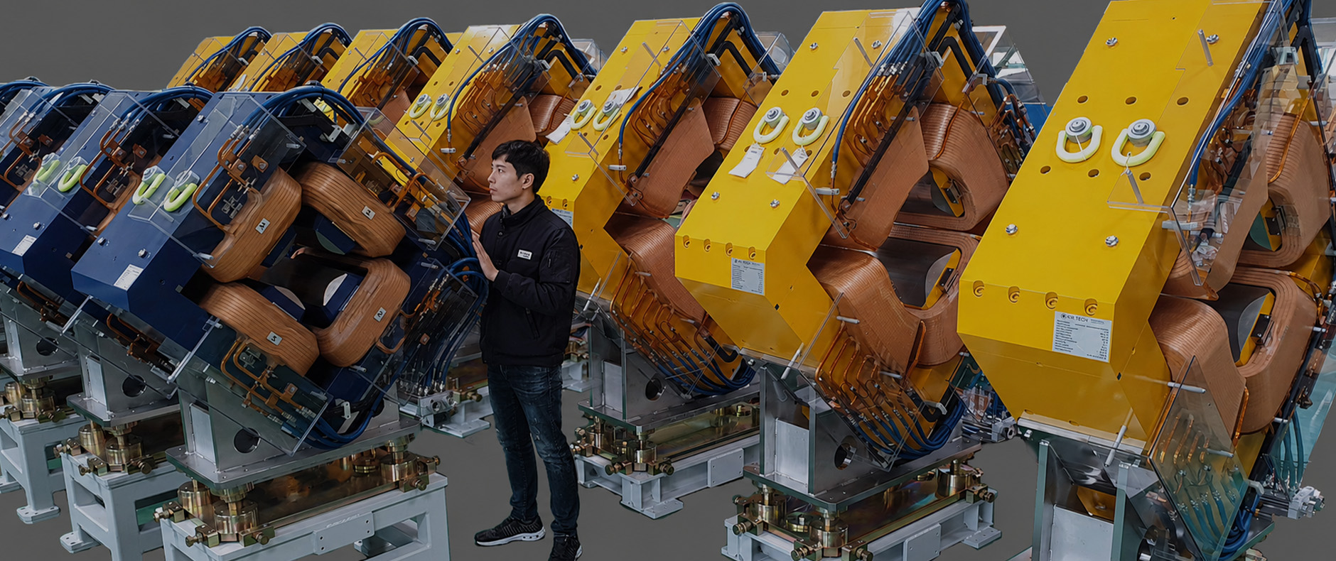 A technician inspecting the copper coil structure inside a large orange and blue quadrupole magnet device