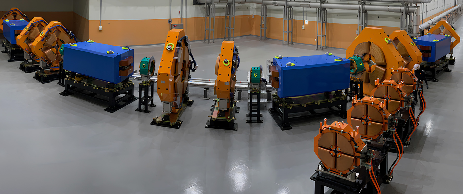 Line of blue and orange particle accelerator equipment inside facility
