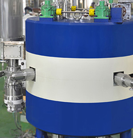 Cylindrical blue and white cyclotron magnet unit with beam port connections